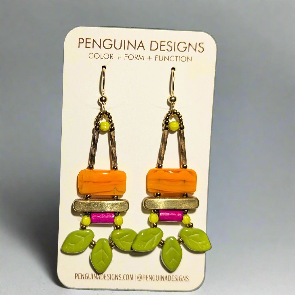 Brightly colored earrings on a paper card. The earrings have orange rectangles with gold bars and bright green leaves below them.