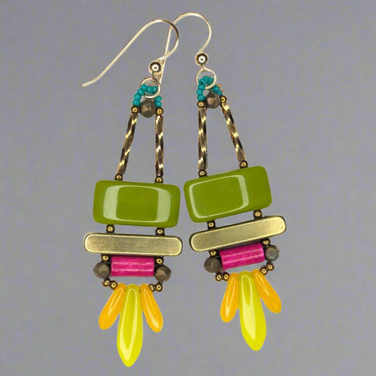 Long earrings that have a wide avocado rectangle stacked on top of a brass colored bar. Under the bar there is a bright magenta tube and a swag of two small orange dagger beads on either side of a bigge chartreuse dagger.