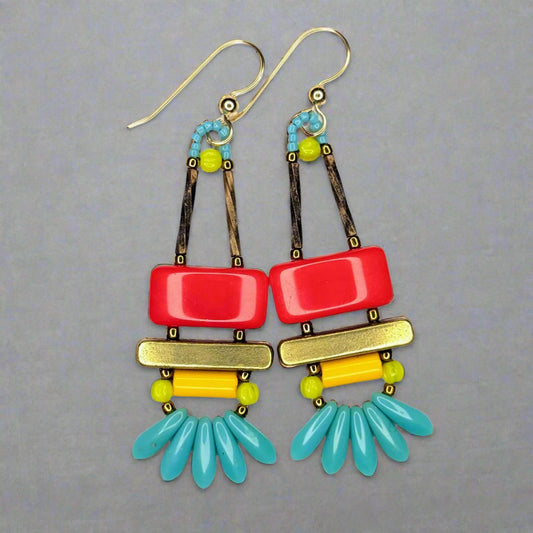 The earrings each have a wide red rectangle stacked on top of a brass colored bar. Under the bar there is light orange tube, five small turquoise daggers and tiny chartreuse melon accents.